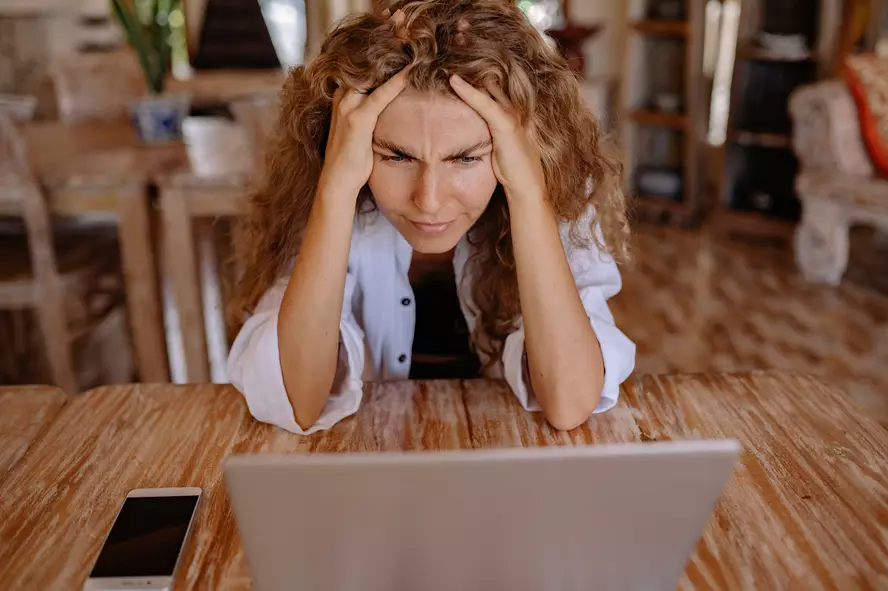 a lady sitting in front of the laptop and consideriing thing